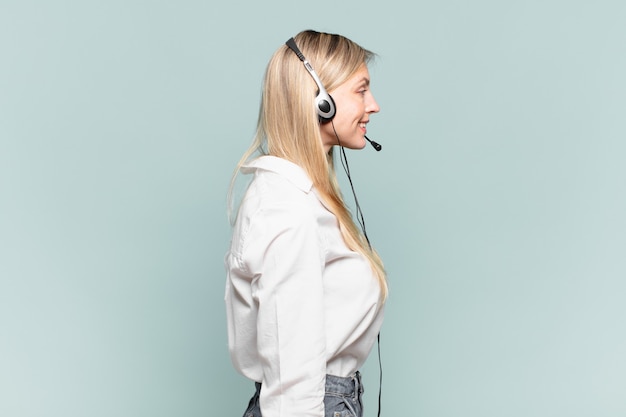 Young blond telemarketer woman on profile view looking to copy space ahead, thinking, imagining or daydreaming