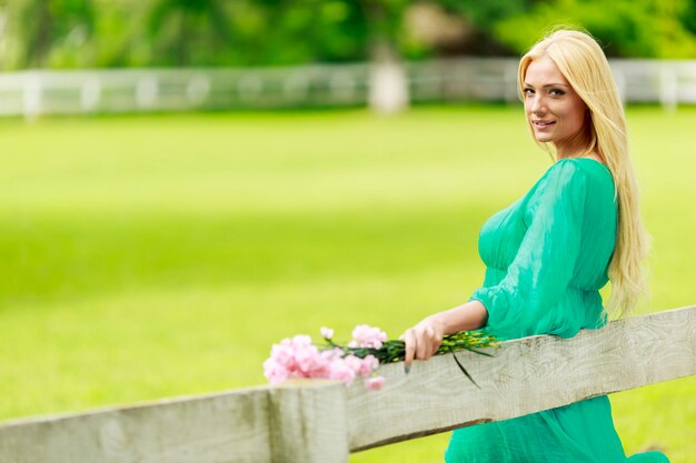 Young blond woman by the fence