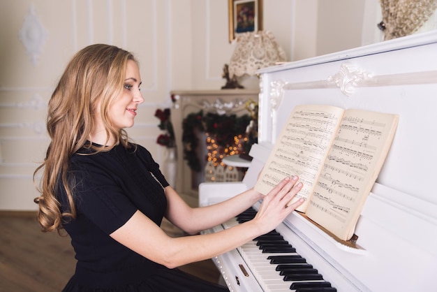 Foto la giovane donna bionda non suona il pianoforte bianco