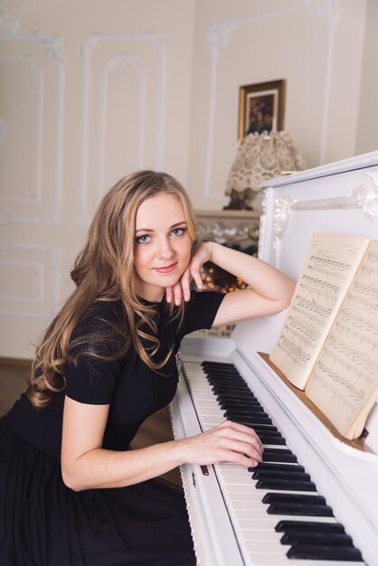 Young blond woman play no white piano