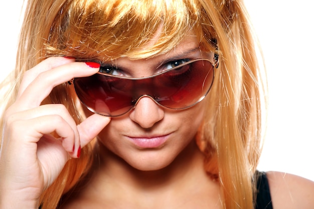 Young blond woman posing with her sunglasses against white background