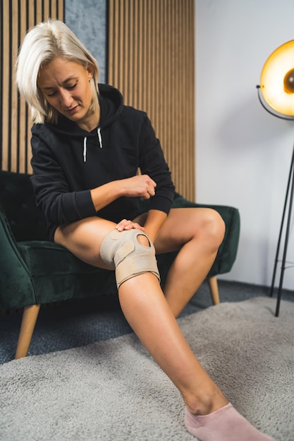 A young blond woman recovering from injuries at home and using a knee brace