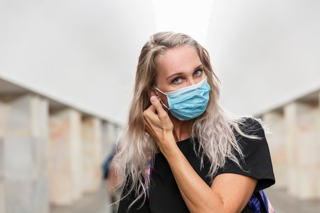 Young blond woman in the subway puts on a medical mask