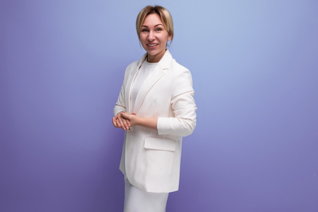 Young blond woman wearing jacket and dress posing confidently on purple background with copy space