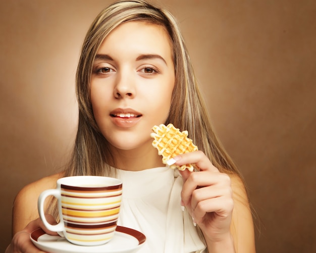 Young blond woman with coffee and cookies.