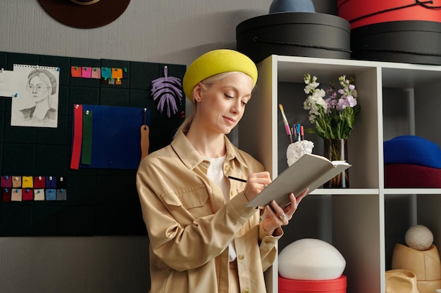 Young blond woman with notebook making notes or drawing sketches