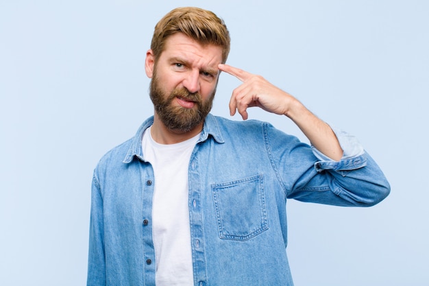 Young blonde adult man feeling confused and puzzled, showing you are insane, crazy or out of your mind