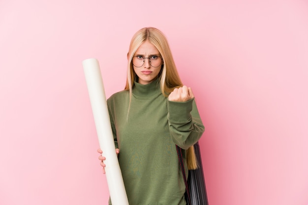 Young blonde architecture student showing fist to camera, aggressive facial expression.