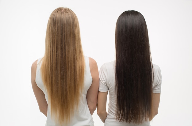 Photo young blonde and brunette women stand back and show their beautiful hair