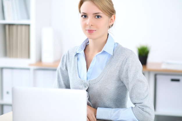 Young blonde business woman with laptop in the office Business concept