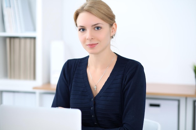 Young blonde business woman with laptop in the office. Business concept.