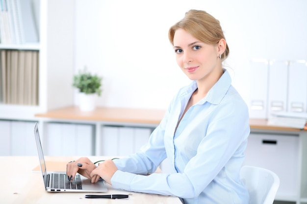 Young blonde business woman with laptop in the office. Business concept.