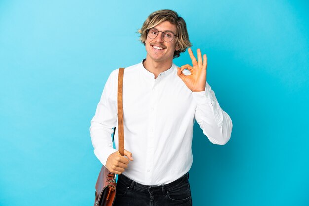 Young blonde businessman isolated on blue background showing ok sign with fingers