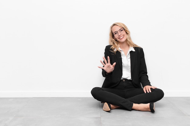 Young blonde businesswoman sitting on a cement floor with a copy space