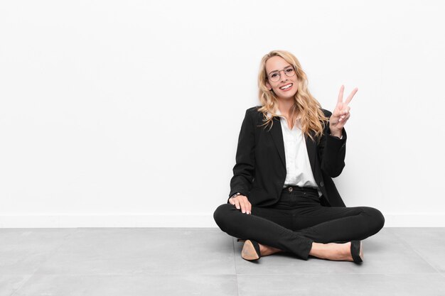 Young blonde businesswoman sitting on a cement floor with a copy space