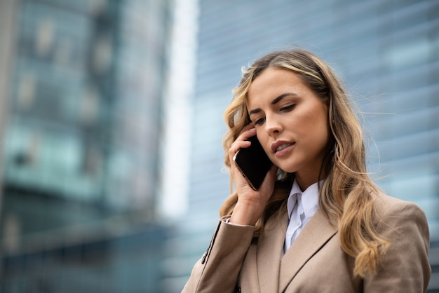 Bionda e giovane imprenditrice parlando al telefono in una strada cittadina