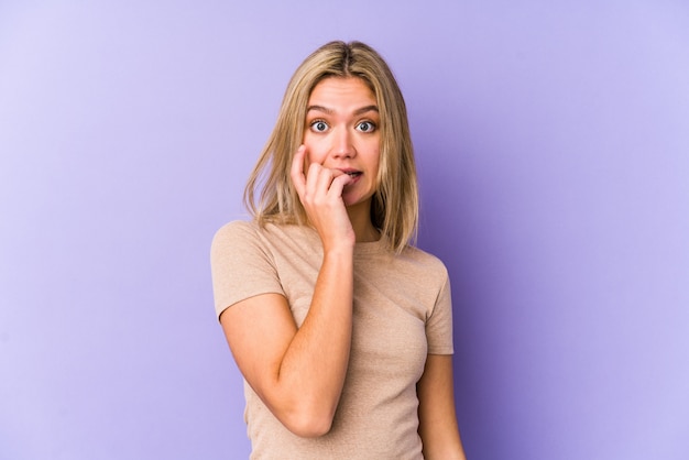 Young blonde caucasian woman biting fingernails, nervous and very anxious.