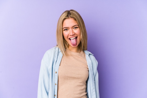 Young blonde caucasian woman funny and friendly sticking out tongue.