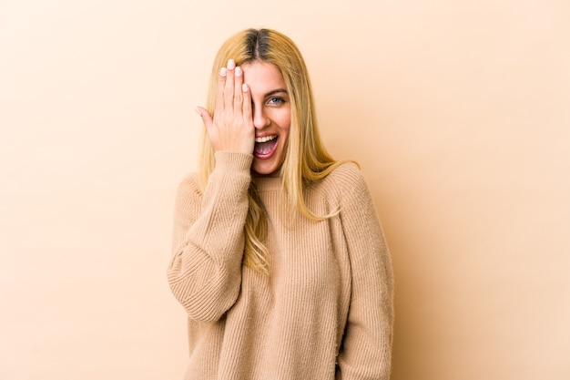 Young blonde caucasian woman having fun covering half of face with palm.