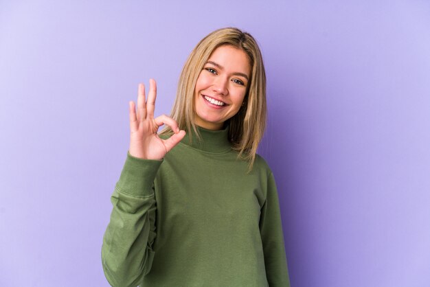 Young blonde caucasian woman isolated cheerful and confident showing ok gesture.