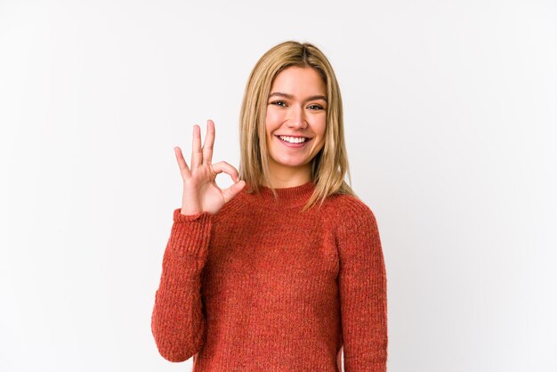 Young blonde caucasian woman isolated cheerful and confident showing ok gesture.