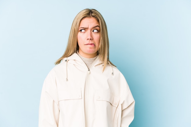 Young blonde caucasian woman isolated confused, feels doubtful and unsure.