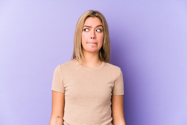 Young blonde caucasian woman isolated confused, feels doubtful and unsure.