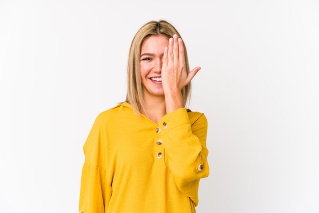 Young blonde caucasian woman isolated having fun covering half of face with palm.