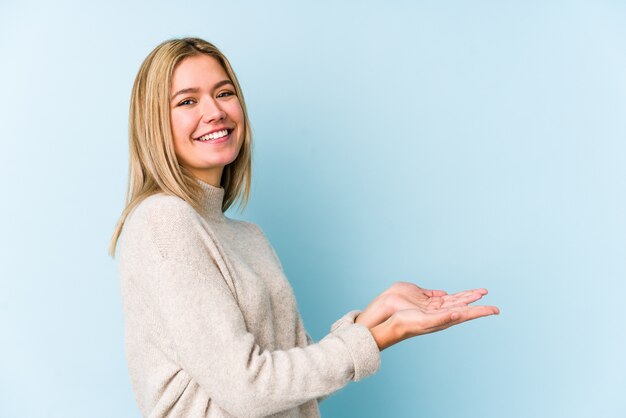 手のひらにコピースペースを持って分離された若い金髪白人女性。