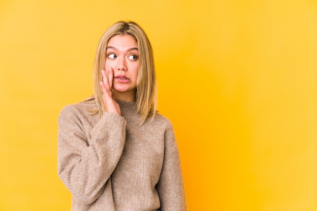 Young blonde caucasian woman isolated is saying a secret hot braking news and looking aside