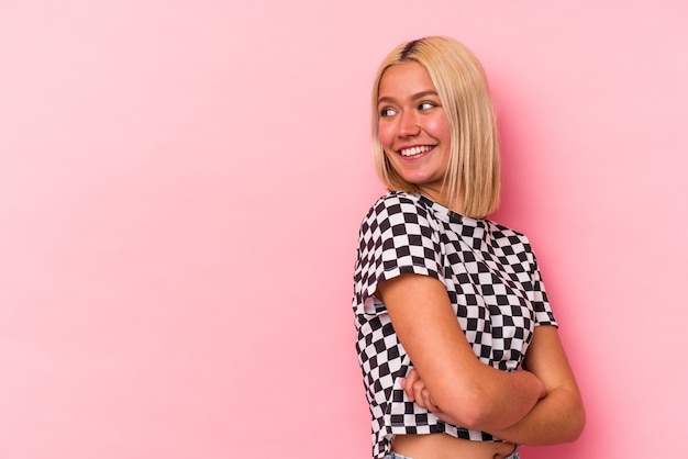 Young blonde caucasian woman isolated on pink background
