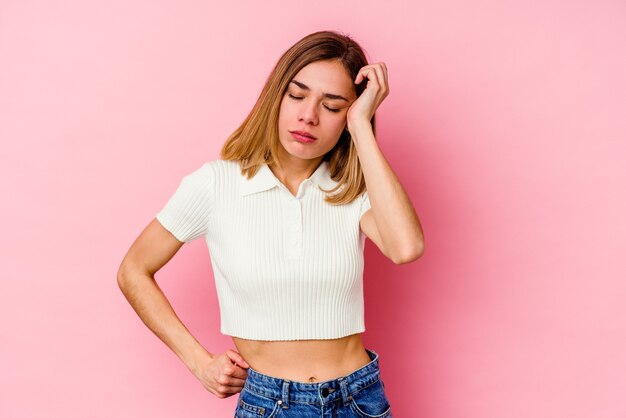 Young blonde caucasian woman isolated on pink background