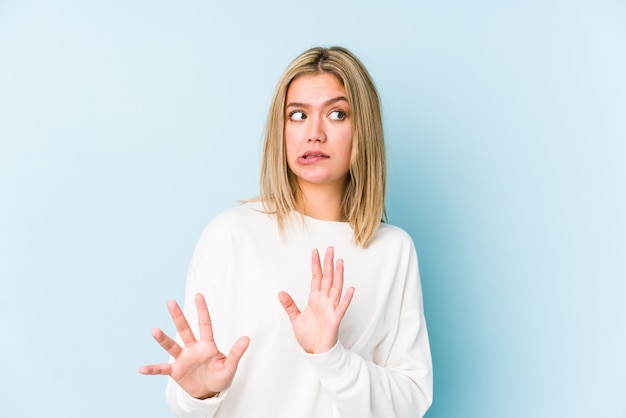 Young blonde caucasian woman isolated rejecting someone showing a gesture of disgust.