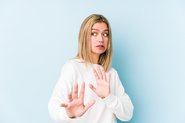 Young blonde caucasian woman isolated rejecting someone showing a gesture of disgust.