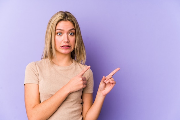 Young blonde caucasian woman isolated shocked pointing with index fingers to a copy space.