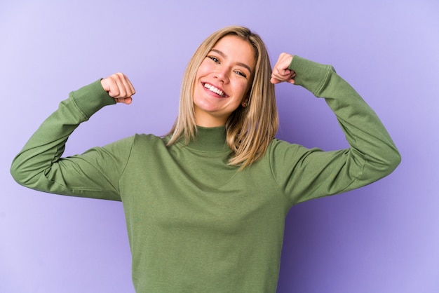 Young blonde caucasian woman isolated showing strength gesture with arms, symbol of feminine power