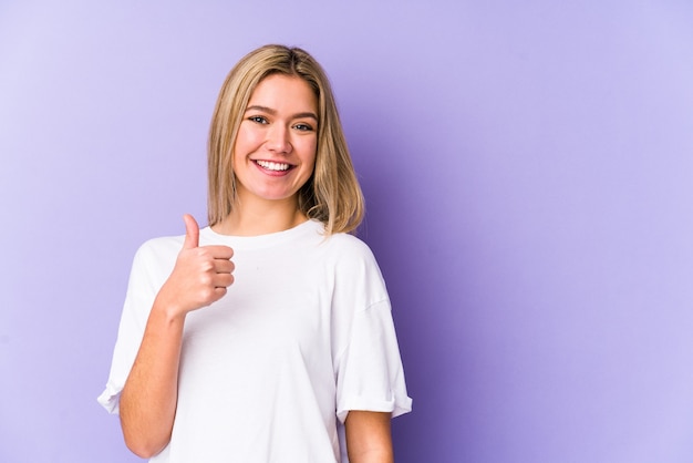 Young blonde caucasian woman isolated smiling and raising thumb up