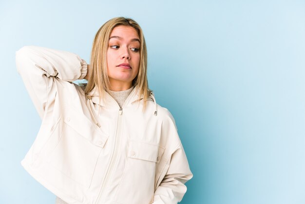 Photo young blonde caucasian woman isolated touching back of head, thinking and making a choice.