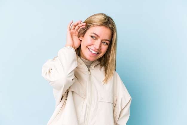 Young blonde caucasian woman isolated trying to listening a gossip.