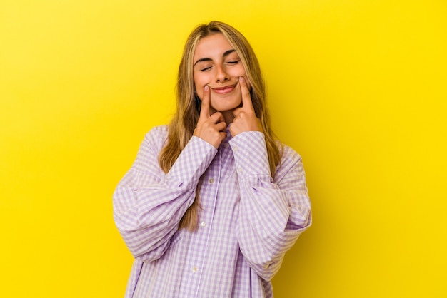 Young blonde caucasian woman isolated on yellow background doubting between two options.