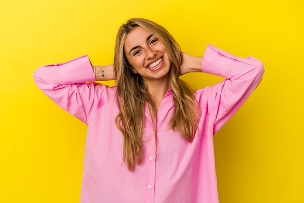 Young blonde caucasian woman isolated on yellow background stretching arms, relaxed position.