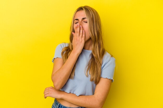 Young blonde caucasian woman   yawning showing a tired gesture covering mouth with hand.