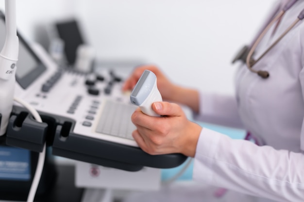 Young blonde doctor working on ultrasound machine in new clinic. Healthcare concept