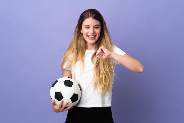놀라운 표정으로 보라색 공간에 고립 된 젊은 금발의 축구 선수 여자