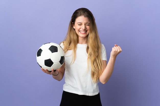 Молодая блондинка футболист женщина на фиолетовом празднует победу в позиции победителя