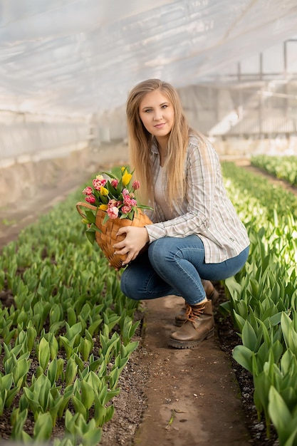 a young blonde girl holds a straw bag with colorful tulips in her hands