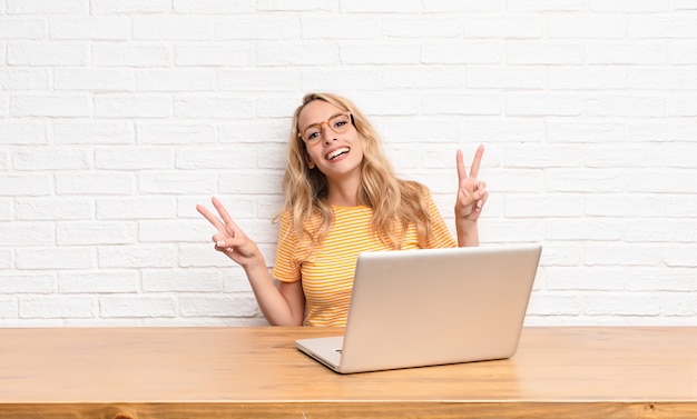 young blonde girl at laptop smiling and looking happy