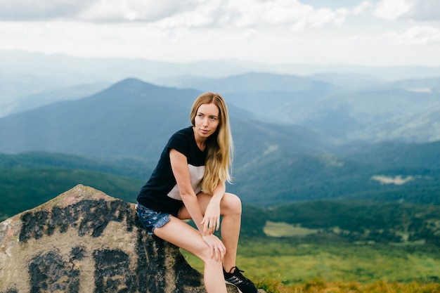 Young blonde girl posing in mountains