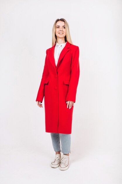 Young blonde girl in a red coat on a white 