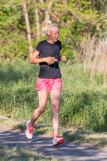 Young blonde girl running on the bike path